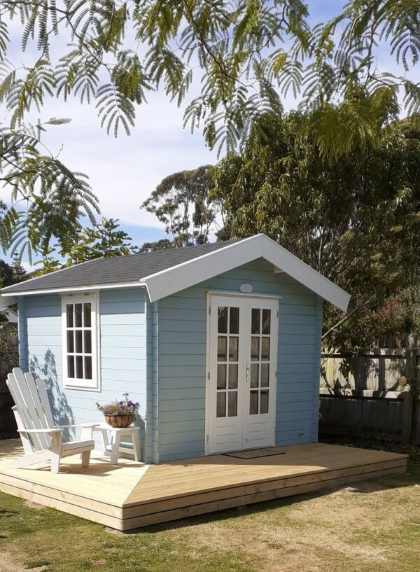 blue and white log cabin built with a custom deck nz